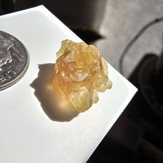 May include: A cluster of small, translucent, yellow-brown crystals with a shiny, glassy surface.